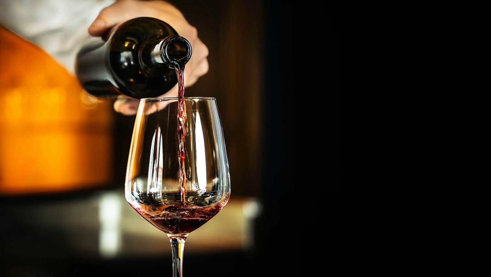 Barman pouring red wine into a glass. Hospitality, beverage and wine concept